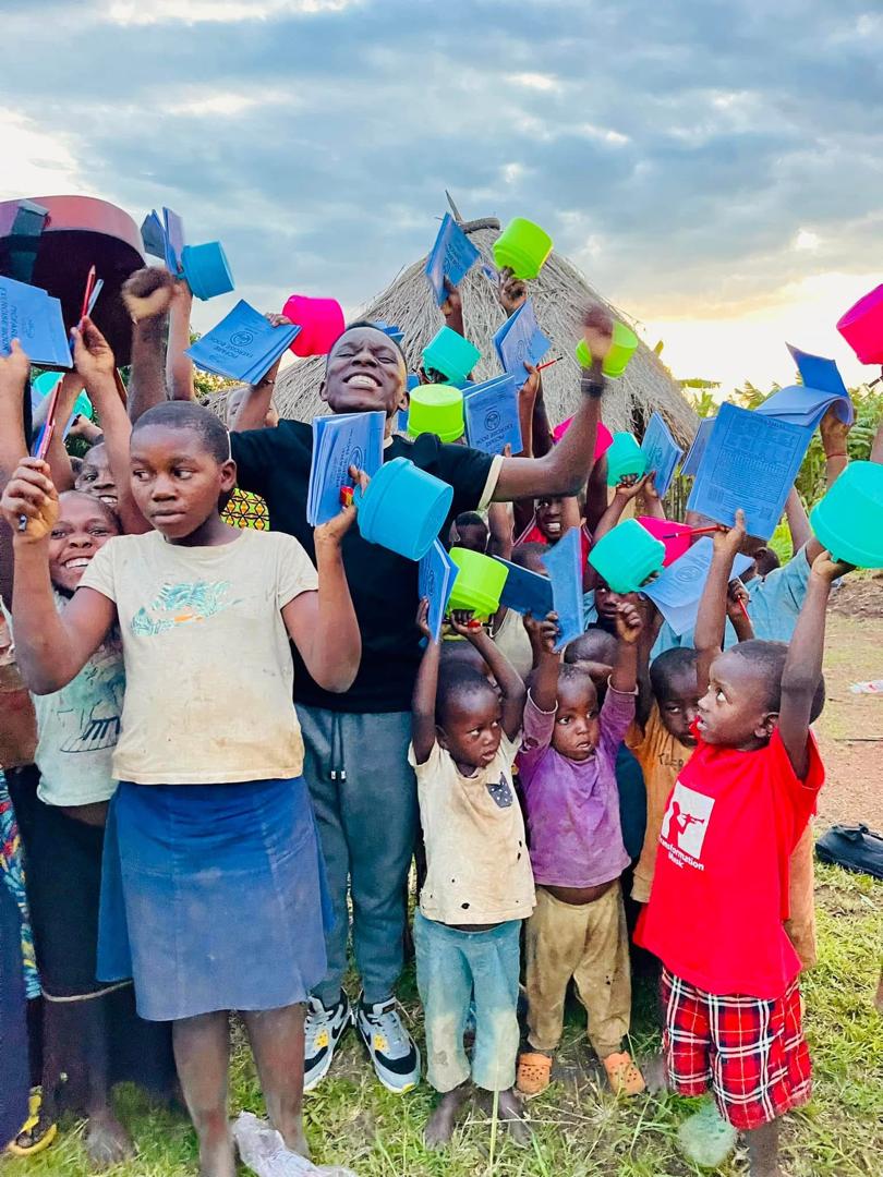 Children at Destiny Transformation Home cheering with new exercise books and cups raised in the air